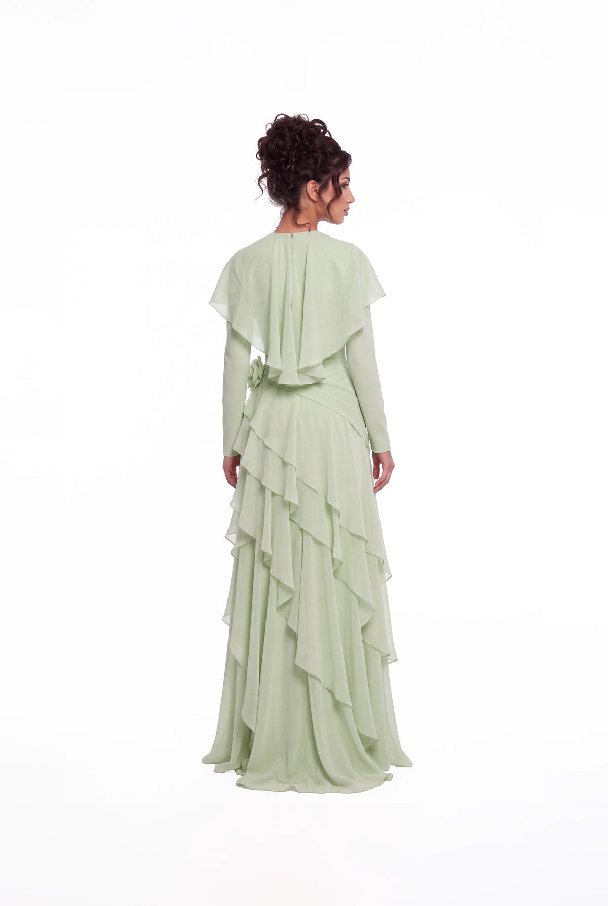 Back view of the Athera sage green chiffon gown showing the short cape and cascading ruffle tiers
