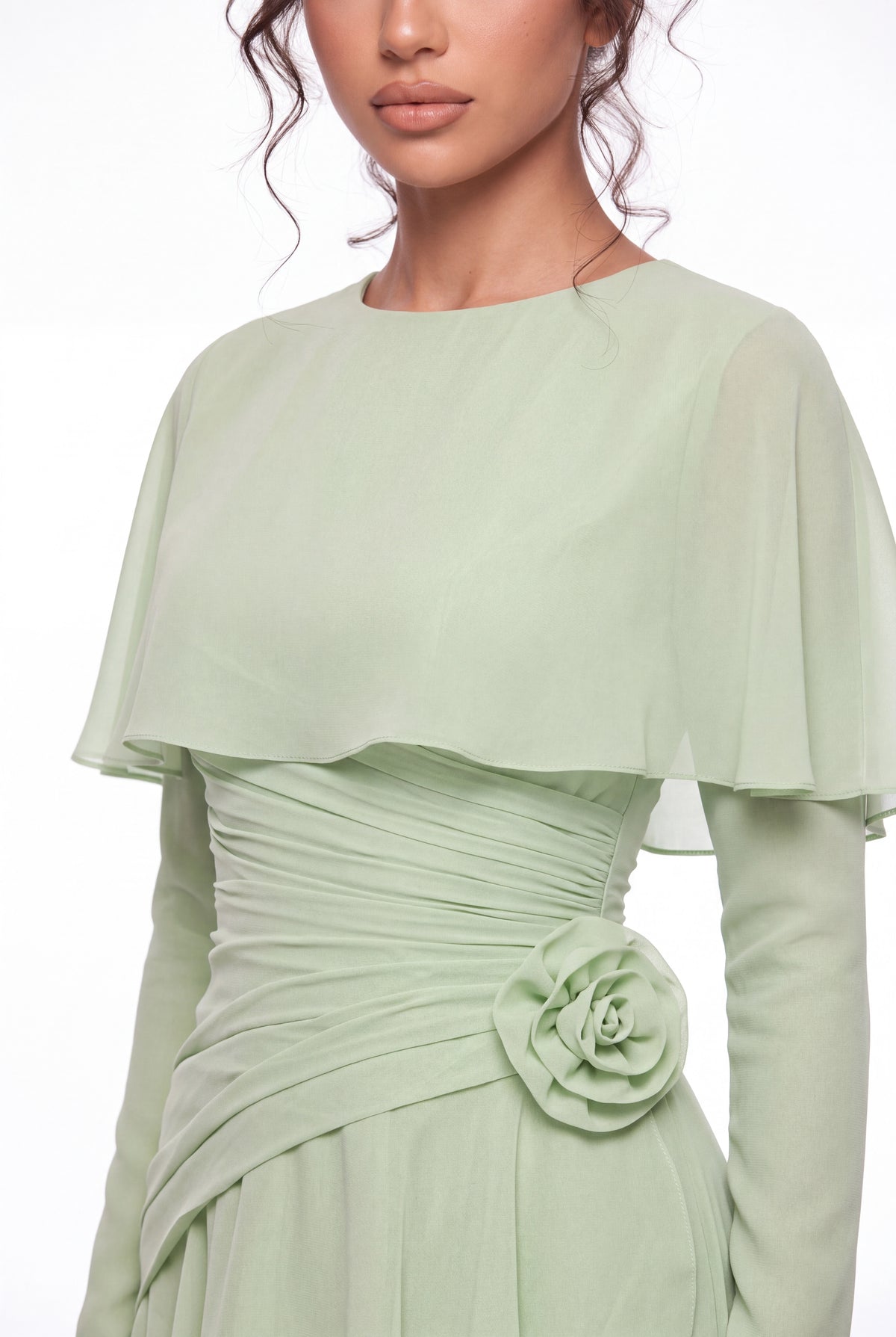Close-up of the Athera sage green gown: chiffon cape, gathered waist and hand-formed chiffon rose